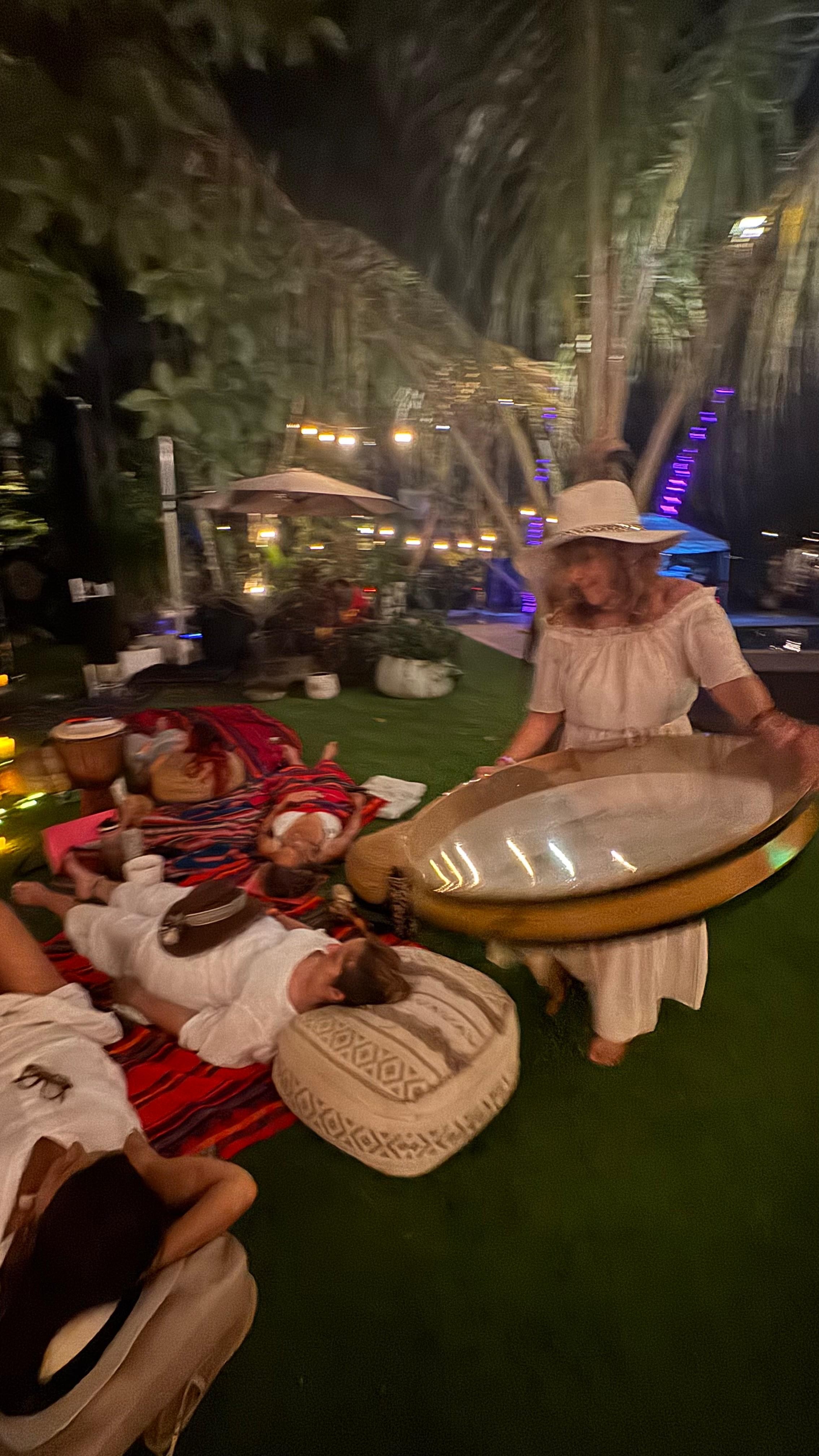 Diana carrying a resonating bowl over resting participants during a nighttime lawn sound journey