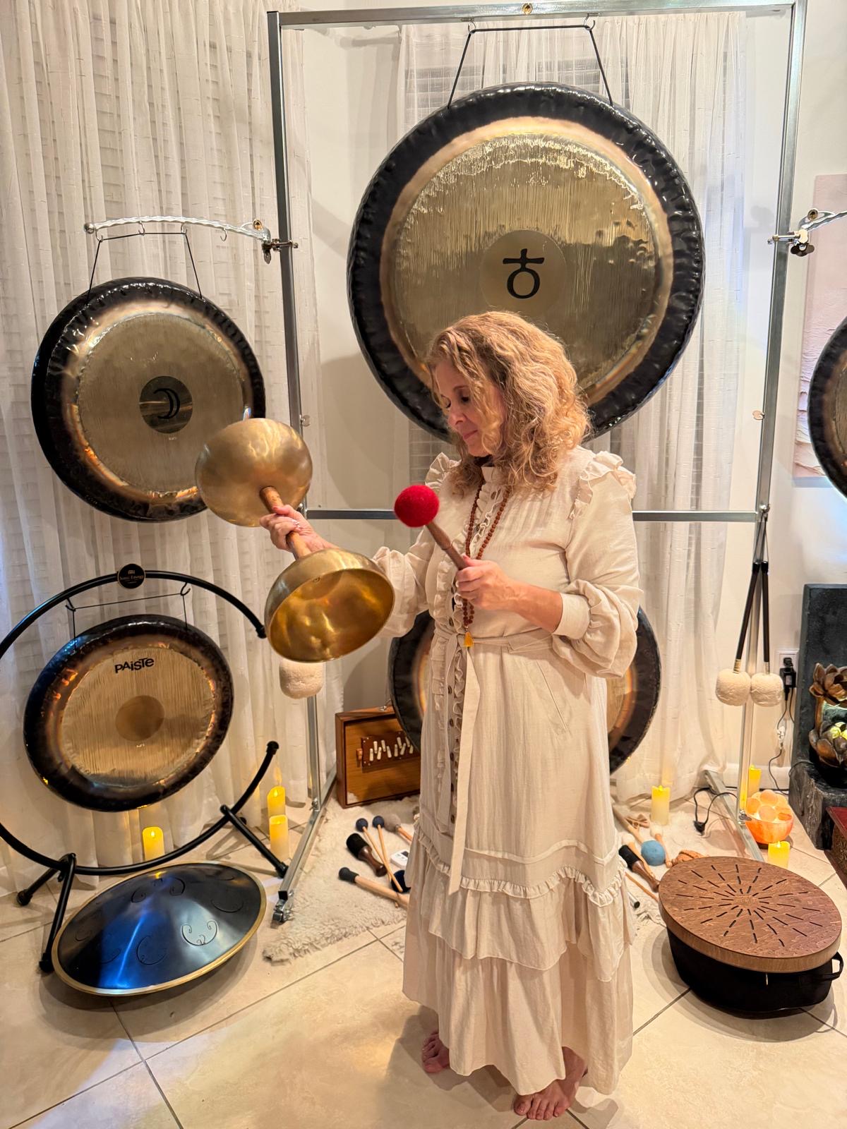 Diana Mylene Sawal holding resonant singing bowls among her collection of gongs